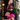 Woman in a burgundy jacket and pink feather skirt carrying the Hadley Pollet Kiss-Lock Frame Birdie Bag on a gold chain strap