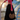 Woman in a long black skirt holding the Brown Peek-a-Boo Bag by Hadley Pollet beside a glass spiral staircase