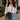 Woman in a linen shirt and jeans wearing the Custom Bucket Bag by Hadley Pollet, black with pink and green trim and tassel