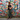 Woman in front of a colorful graffiti wall holding the Walnut Peek-A-Boo Clutch by Hadley Pollet